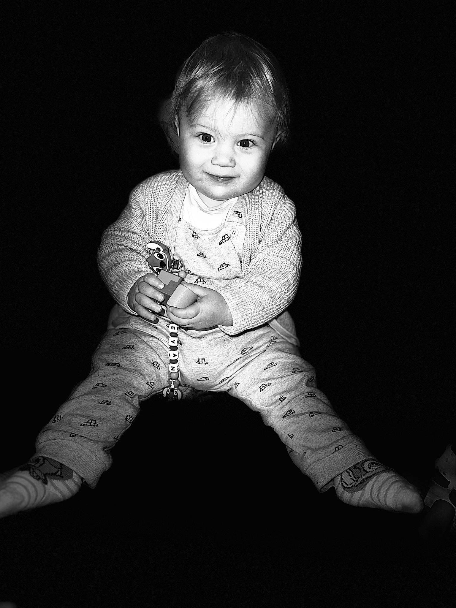 Leyan a rejoint le concours — aidez-le/la à gagner de superbes lots ! baby, baby_toddler_clothing, black_and_white, cheek, child, darkness, eye, flash_photography, flooring, grass, hair, happy, head, human_body, monochrome, monochrome_photography, person, sitting, sleeve, smile