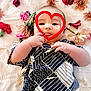 Zen is registered to the contest to win money with this photo: baby, infant, heart_shape, flowers, pink_flowers, red_flowers, blanket, patterned_clothing, tongue_out, cute, playful, soft_texture, lying_down, hand, face, portrait, child, adorable, decorative, peaceful