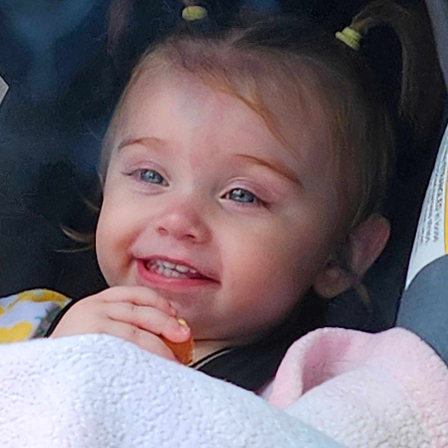 Julie joined the competition — help win amazing prizes! toddler, child, smiling, pigtails, blanket, snack, blue_eyes, happy, cute, portrait, face, indoors, baby, cozy, clothing, person, young_child, closeup, seated, comfort