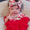 Julie is registered to the contest to win money with this photo: baby, infant, child, headband, strawberry_pattern, red_tutu, clothing, cute, expression, face, sitting, cushion, checkered_pattern, indoors, person, funny_face, portrait, soft_background, smile, young_child