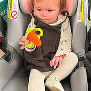 Isabella joined the competition — help win amazing prizes! baby, car_seat, toy, child, infant, clothing, white_shoes, black_dress, tights, seat, child_safety, indoor, diapers, cute, holding, small_hand, face, car_interior, child_toy, infant_toy