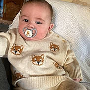 Akis a rejoint le concours — aidez-le/la à gagner de superbes lots ! baby, pacifier, knitwear, fox_pattern, cream_color, indoor, couch, blanket, face, child, comfort, cute, relaxing, portrait, infant, sweater, pants, home, pacifier_clip, soft_lighting