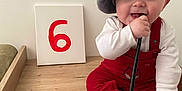Akis a rejoint le concours — aidez-le/la à gagner de superbes lots ! baby, beret, paintbrush, red_overalls, white_shirt, canvas, number_six, wooden_surface, sitting, happy, smiling, face, chewing, milestone, indoor, cute, child, person, sock, celebration