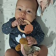 Inès participe au concours pour gagner de l'argent avec cette photo : baby, infant, teething_ring, soft_toy, blanket, stars, clothing, onesie, hand, foot, face, head, eyes, cute, indoor, lying_down, child, person, toy, nursery