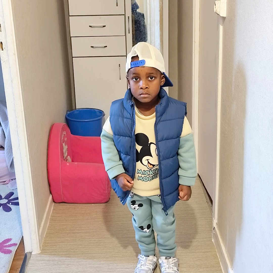 Ansry a rejoint le concours — aidez-le/la à gagner de superbes lots ! boy, bucket, cabinet, cap, chair, child, clothing, floor, hallway, indoor, mickey_mouse, pants, person, portrait, puffer_vest, serious_expression, sneakers, standing, sweatshirt, wall