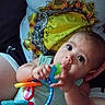 baby, infant, toy, teething_toy, person, hand, clothing, colorful, sunflower, pattern, portrait, cute, child, skin, face, eyes, sitting, holding, comfort, casual
