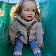 Loé a rejoint le concours — aidez-le/la à gagner de superbes lots ! child, toddler, slide, playground, jacket, fleece, socks, shoes, outdoor, sunlight, tree, play, young_child, curly_hair, casual_clothing, park, fun, happy, closeup, daytime