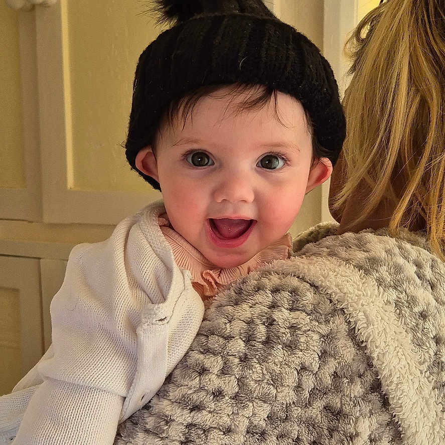 Elsie joined the competition — help win amazing prizes! baby, bonnet, cap, clothing, coat, costume, face, happy, hat, head, hoodie, jacket, knitwear, pants, person, photography, portrait, smile, sweater, sweatshirt
