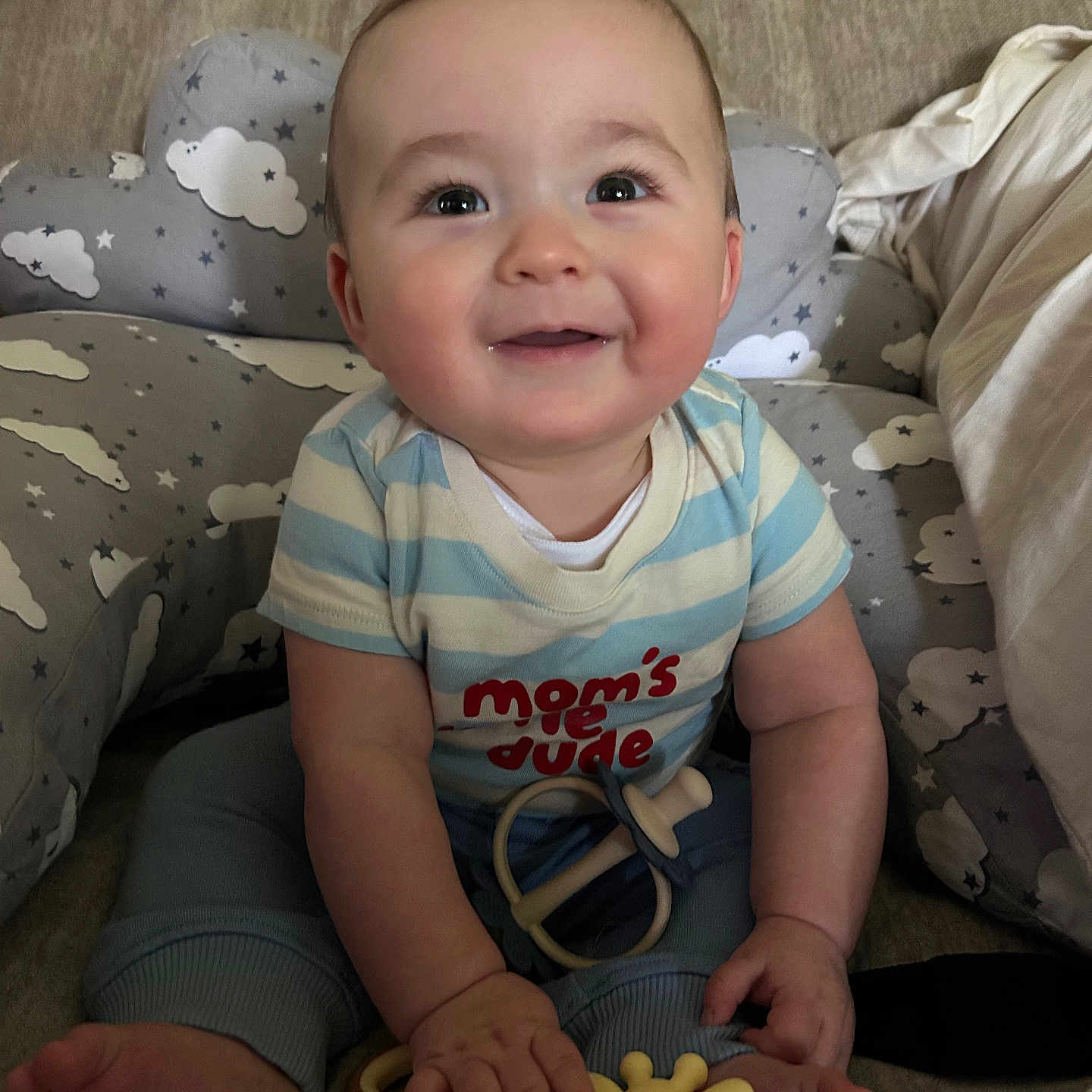 Jethro is registered to the contest to win money with this photo: baby, child, smiling, happy, toy, giraffe_toy, cushion, cloud_pattern, blue_clothing, striped_shirt, sitting, indoors, infant, cute, chubby_cheeks, playful, person, portrait, comfort, home