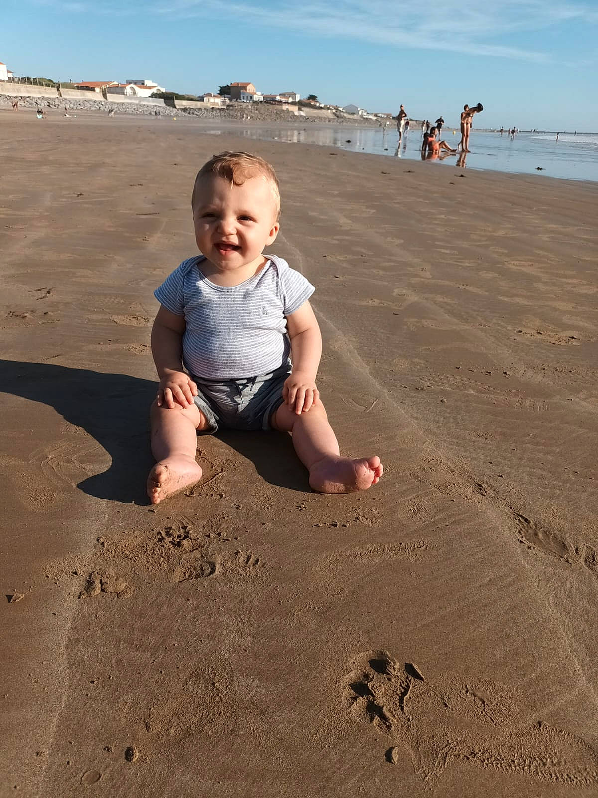Robin a rejoint le concours — aidez-le/la à gagner de superbes lots ! beach, ecoregion, fun, gesture, happy, horizon, landscape, morning, people_in_nature, people_on_beach, person, sand, shore, shorts, singing_sand, sky, smile, standing, summer, toddler