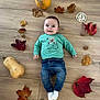 autumn_leaves, baby, child, clothing, cute, face, fall, floor, indoor, infant, jeans, milestone_marker, person, portrait, pumpkin, seasonal, smiling, socks, walnuts, wooden_floor
