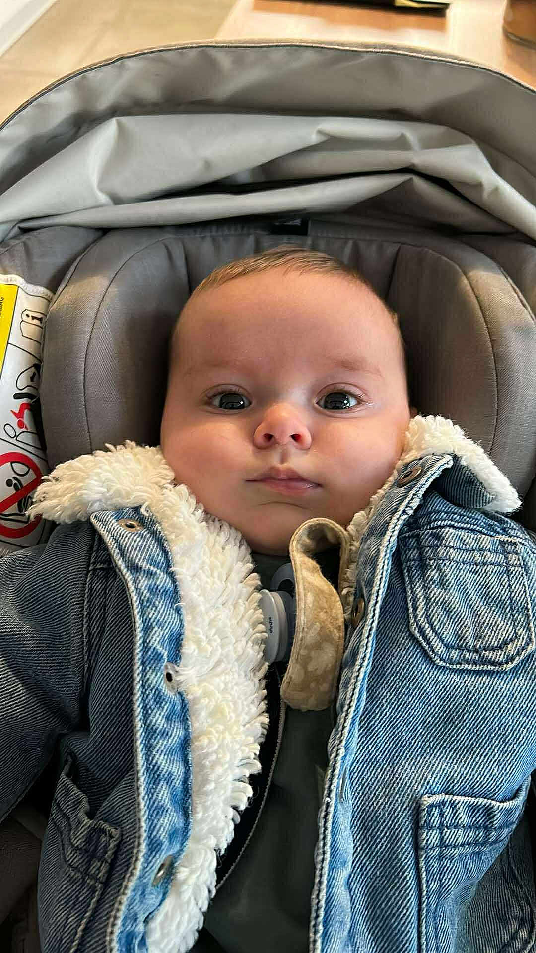 Louis a rejoint le concours — aidez-le/la à gagner de superbes lots ! baby, infant, denim_jacket, car_seat, pacifier, fur_lining, clothing, child, cute, portrait, indoor, seated, young_child, face, head, eyes, expression, warm_clothes, comfort, casual
