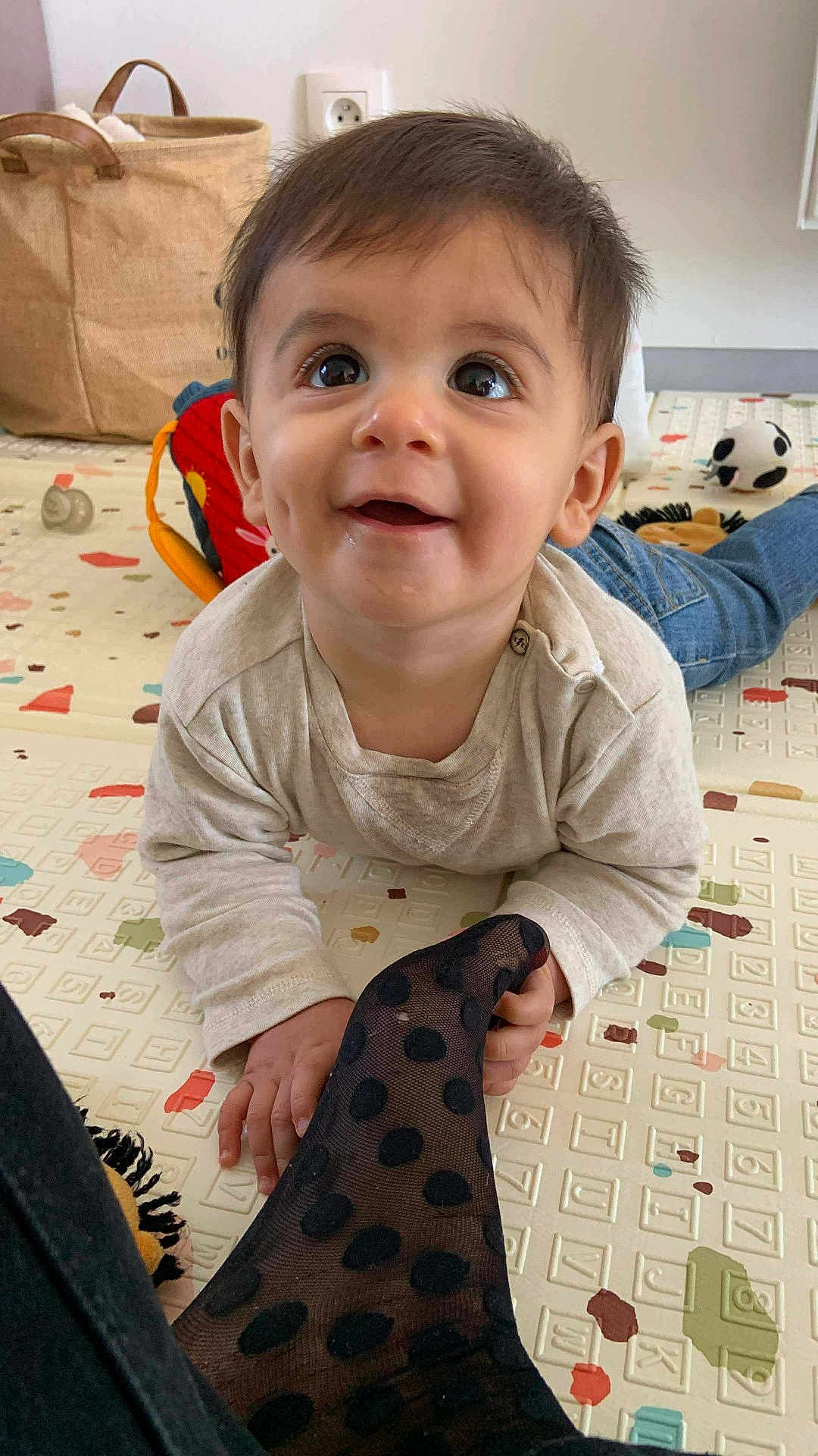 Leon participe au concours pour gagner de l'argent avec cette photo : baby, child, crawling, polka_dot, sock, play_mat, toy, basket, indoor, cute, dimples, curious, happy, clothing, floor, person, head, face, smiling, jeans