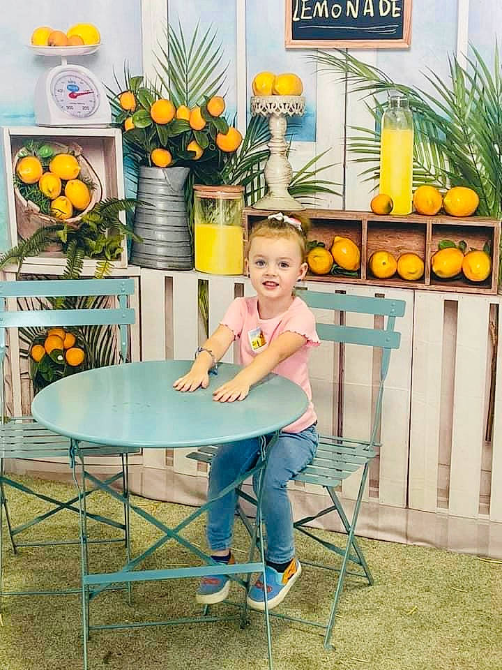 Sherry joined the competition — help win amazing prizes! chair, floral_design, flower, flower_arranging, flowerpot, happy, houseplant, joy, leisure, orange, outdoor_furniture, outdoor_table, person, plant, room, shorts, sitting, smile, table, toddler