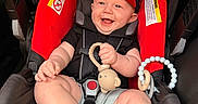 Jaxon joined the competition — help win amazing prizes! baby, child, car_seat, smile, hat, toy, monkey_toy, black_shoes, socks, clothing, happy, infant, seatbelt, red, black, person, cute, portrait, indoor, baby_toy