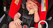 Jaxon is registered to the contest to win money with this photo: baby, black_shirt, black_shoes, blue_striped_socks, cap, car_seat, child, childhood, comfort, cute, face, footwear, gray_shorts, hand, indoor, infant, red_car_seat, seat_belt, smiling, toy