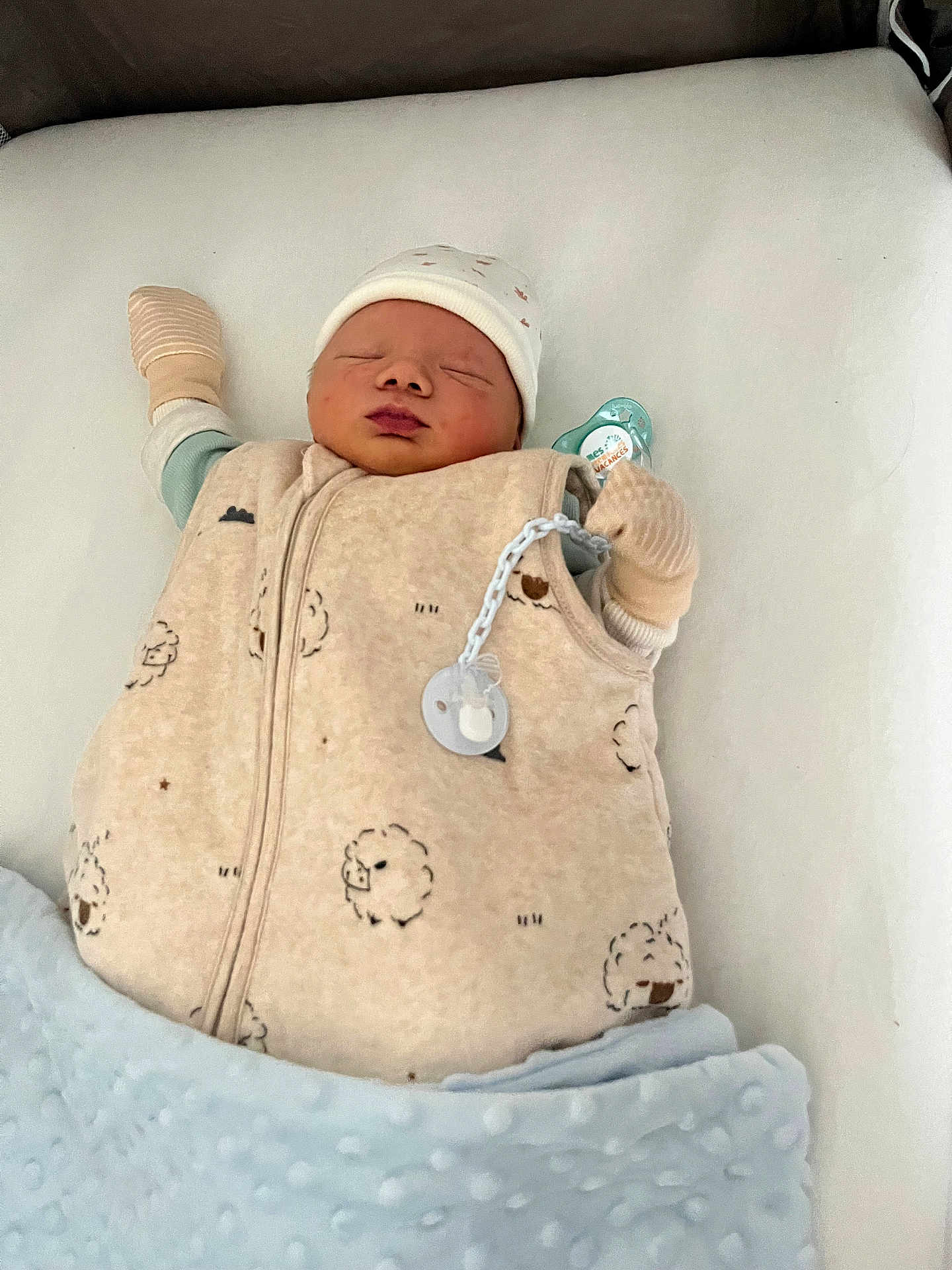 élian participe au concours pour gagner de l'argent avec cette photo : newborn, baby, sleeping, infant, blanket, mittens, hat, sleeping_bag, cozy, cute, soft, indoors, child, resting, peaceful, white_background, blue_blanket, closeup, face, pacifier