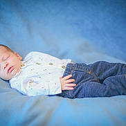 Abel is registered to the contest to win money with this photo: baby, infant, sleeping, portrait, lying_down, blanket, blue_background, clothing, jeans, shirt, bare_feet, peaceful, indoors, close_up, soft_lighting, photography, face, hand, legs, newborn