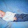 baby, infant, sleeping, portrait, lying_down, blanket, blue_background, clothing, jeans, shirt, bare_feet, peaceful, indoors, close_up, soft_lighting, photography, face, hand, legs, newborn