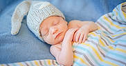 Abel is registered to the contest to win money with this photo: newborn, baby, sleeping, infant, portrait, knitted_hat, blue_blanket, swaddle, striped_clothing, pastel_colors, peaceful, resting, lying_down, closed_eyes, face, hands, soft_lighting, cozy, indoor, child