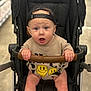 baby, infant, stroller, stroller_handle, cap, backwards_cap, blue_eyes, surprised_expression, gripping, smiley_shirt, onesie, hands, legs, seat, portrait, cute, indoor, shopping_aisle, bokeh, child