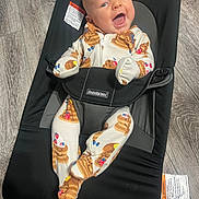 Zane is registered to the contest to win money with this photo: baby, infant, smiling, babybouncer, babybjorn, onesie, pancake_pattern, floor, wooden_floor, happy, clothing, child, cute, indoor, person, seat, baby_seat, joyful, small_child, playful