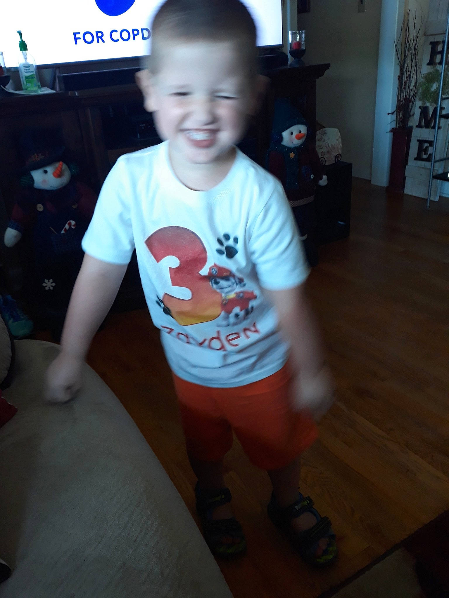 Zayden is registered to the contest to win money with this photo: baby, cheek, child, cool, electronic_device, face, floor, flooring, fun, glasses, head, joy, person, shoe, skin, sleeve, smile, standing, t_shirt, toddler