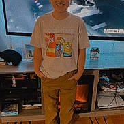 Zayden joined the competition — help win amazing prizes! child, boy, smiling, standing, tshirt, cartoon, pants, socks, indoor, living_room, television, car_interior, furniture, shelf, game_controller, rug, person, home, casual_clothing, electronics