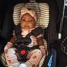 baby, car_seat, infant, child, seatbelt, headband, mittens, clothing, pink, floral_pattern, cute, safety, portrait, indoors, person, child_seat, footwear, expression, face, newborn