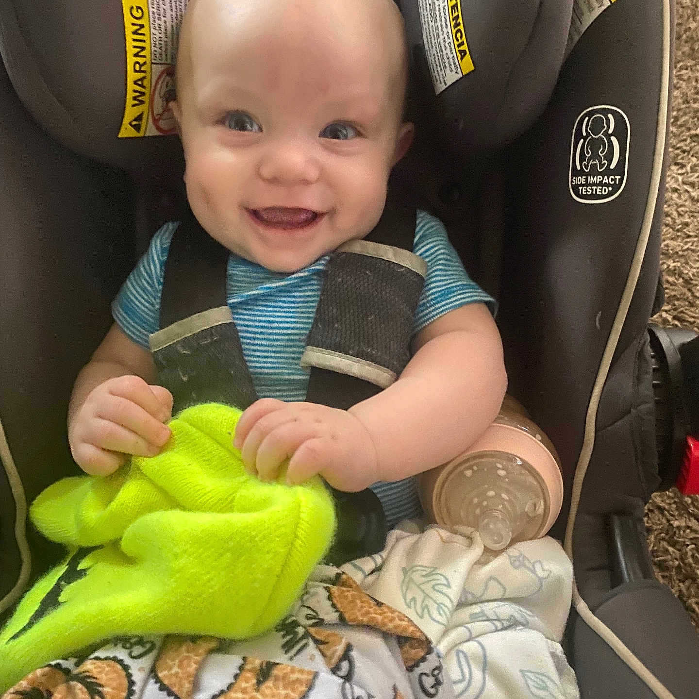 Jaxon joined the competition — help win amazing prizes! baby, smiling, car_seat, blanket, bottle, infant, child, happy, blue_shirt, safety_harness, indoor, cute, clothing, face, person, seat, baby_toy, car_seat_warning_label, holding, comfort