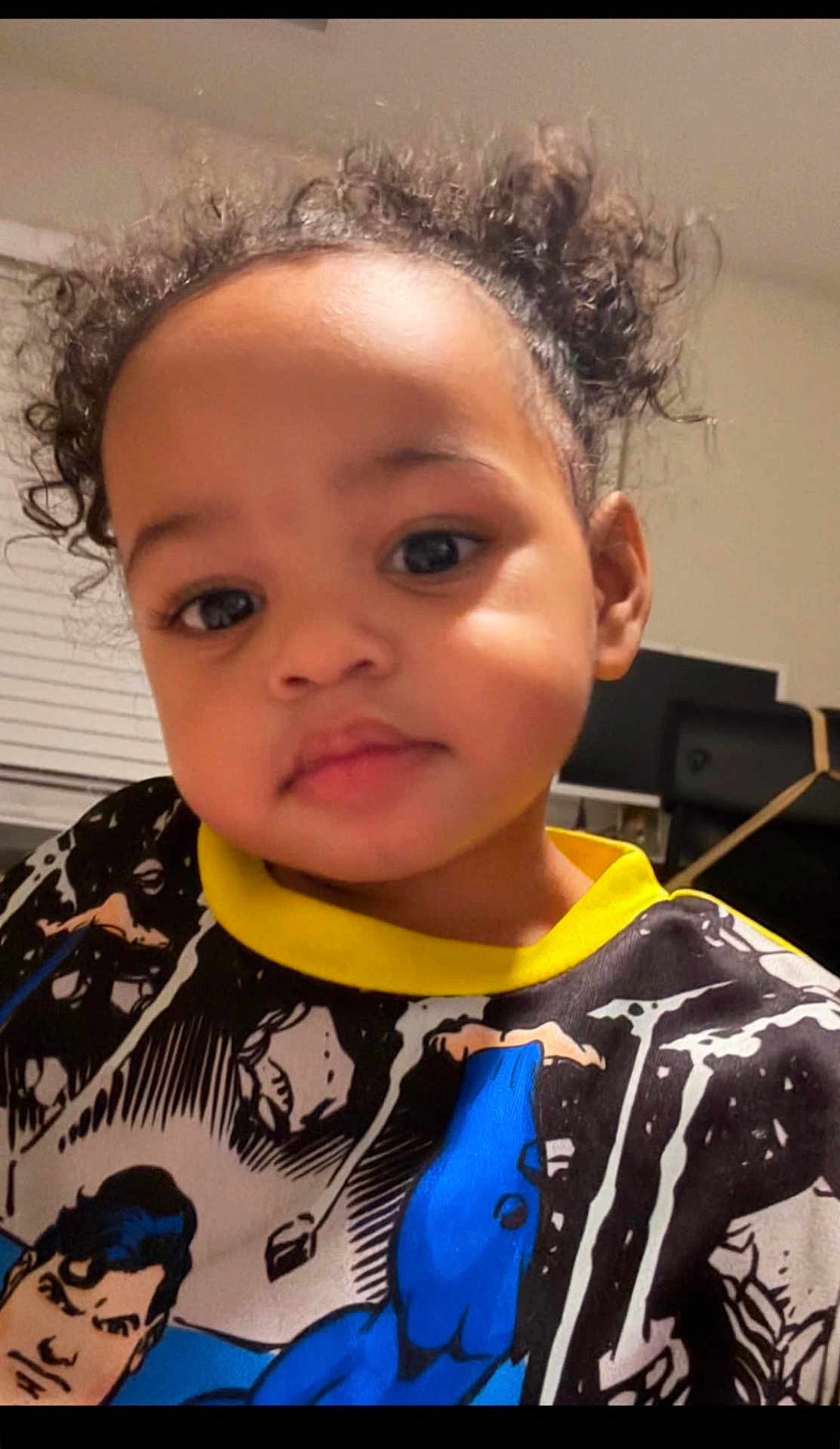 Leilani joined the competition — help win amazing prizes! toddler, child, curly_hair, indoor, portrait, superhero_shirt, face, young_child, black_hair, cute, casual_clothing, expression, person, home, blouse, smiling, closeup, eyebrows, eyelashes, skin