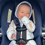 James is registered to the contest to win money with this photo: baby, infant, car_seat, safety_harness, hooded_jacket, plush_clothing, smile, cheek, hand, fingers, seat_buckle, warning_label, stroller_canopy, blue, white, teddy_bear_pattern, portrait, closeup, outdoor, warm_clothing