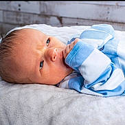 James joined the competition — help win amazing prizes! baby, infant, face, blue_clothing, striped_clothing, blanket, soft_texture, lying_down, closeup, skin, head, newborn, expression, hand, indoors, portrait, cute, small, baby_garment, resting