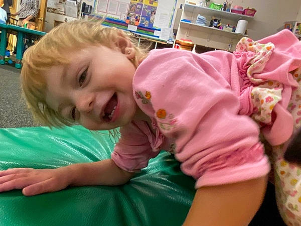 Lucy is registered to the contest to win money with this photo: baby, baby_toddler_clothing, cheek, child, event, fun, happy, kindergarten, laugh, leisure, magenta, nightwear, person, play, recreation, room, shelf, sitting, smile, t_shirt