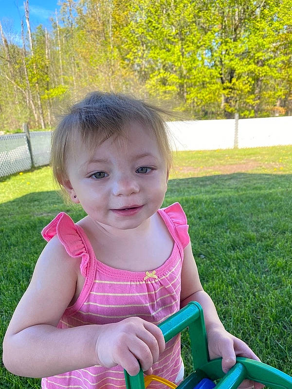 Lucy is registered to the contest to win money with this photo: baby, baby_products, baby_toddler_clothing, child, fun, garden, grass, happy, joy, lawn, leisure, magenta, people_in_nature, person, pink, plant, recreation, riding_toy, sitting, smile