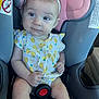 Kaycee is registered to the contest to win money with this photo: baby, child, car_seat, headband, infant, sitting, clothing, patterned_outfit, lemon_print, pink, gray, safety_label, seatbelt, cute, portrait, indoors, person, young_child, face, hands
