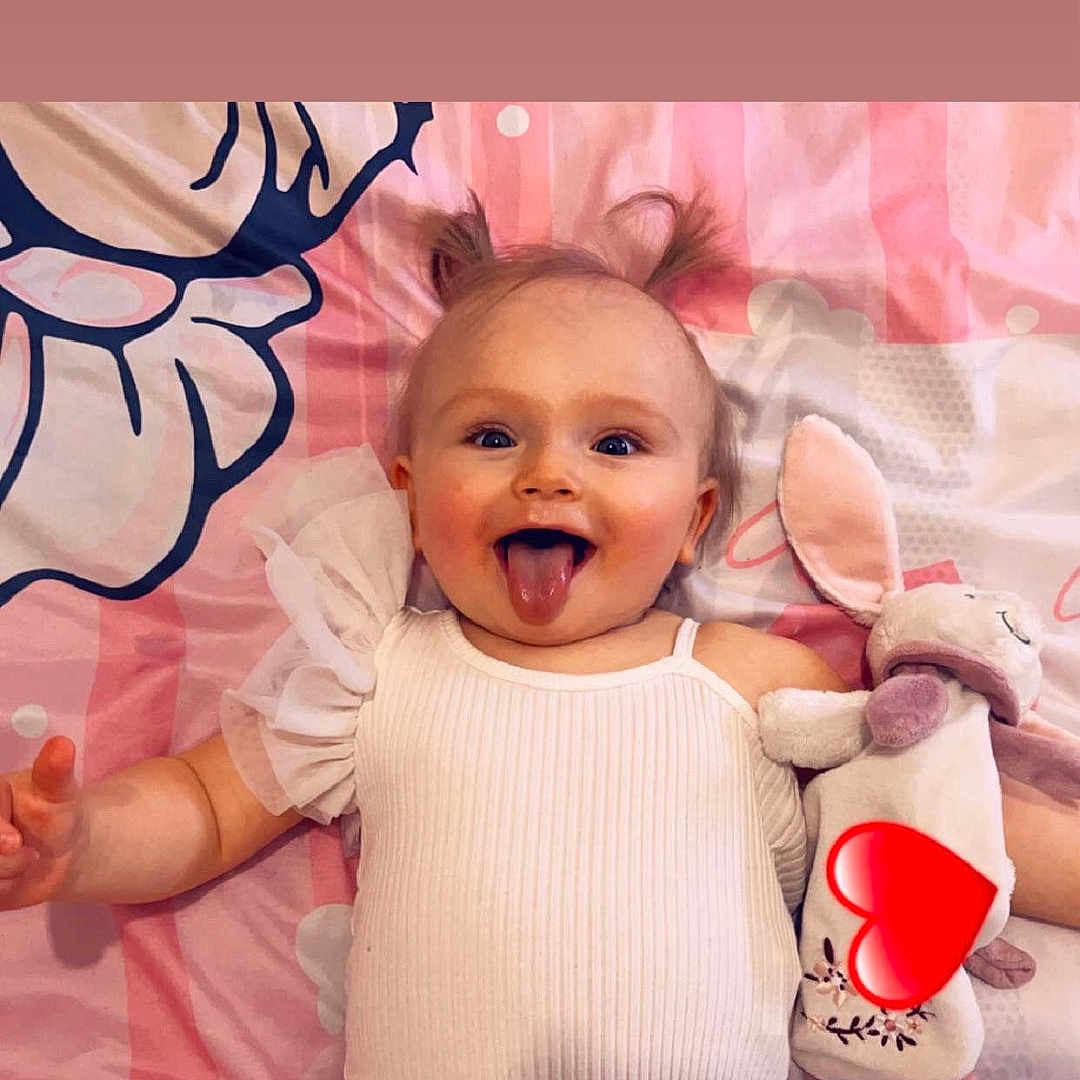 Seya participe au concours pour gagner de l'argent avec cette photo : baby, bunny, child, cute, expression, face, happy, indoor, infant, lying_down, person, pigtails, pink_blanket, playful, smiling, soft_toy, stuffed_animal, tongue_out, toy, white_clothing