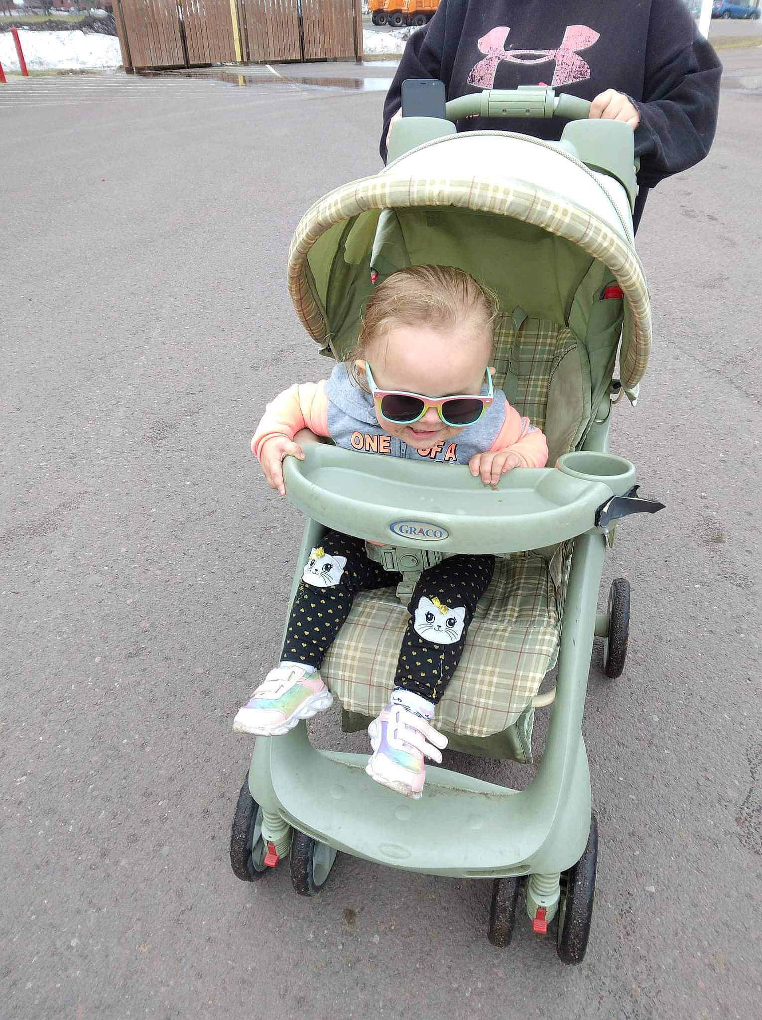 Amariah is registered to the contest to win money with this photo: asphalt, baby, baby_carriage, baby_products, baby_toddler_clothing, cap, child, eyewear, fun, person, personal_protective_equipment, sitting, smile, snapshot, sunglasses, tire, toddler, toy, wheel