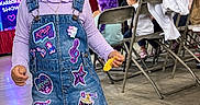 Kehlani is registered to the contest to win money with this photo: child, toddler, girl, portrait, standing, smiling, denim_dress, boots, braids, hair_accessories, k_pop, karaoke, music, stage, indoor, party, colorful_decorations, folding_chairs, snack, crowd