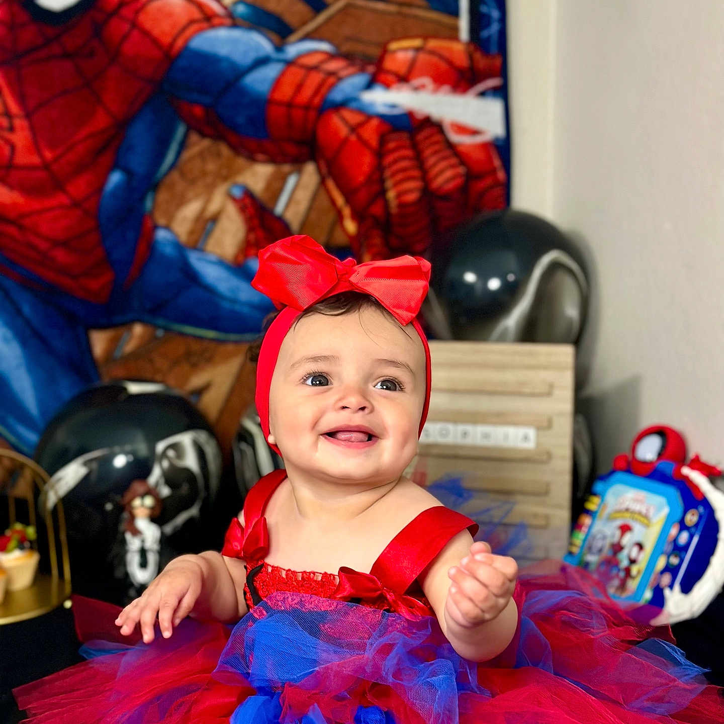 Sophia is registered to the contest to win money with this photo: baby, child, smiling, portrait, indoors, costume, tutu, dress, red, blue, bow, superhero, spiderman, toys, helmet, playroom, birthday, happy, sitting, colorful