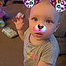 Camilla is registered to the contest to win money with this photo: toddler, child, face_filter, dog_ears, dog_nose, rainbow_colors, curly_hair, blue_eyes, indoor, carpet, sofa, clothing, short_sleeve_shirt, hand, gesture, toy, living_room, digital_filter, cute, portrait