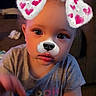 toddler, child, indoor, face_filter, dog_ears, dog_nose, pink_hearts, curly_hair, gray_shirt, expression, reaching_hand, closeup, person, cute, soft_lighting, portrait, young_child, casual_clothing, playful, technology