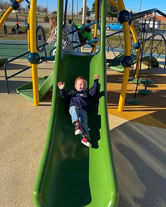 Corbyn is registered to the contest to win money with this photo: baby, baby_toddler_clothing, child, chute, city, fun, grass, green, leisure, nonbuilding_structure, outdoor_play_equipment, outdoor_recreation, person, play, playground, playground_slide, recreation, sky, swing, toddler