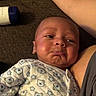 baby, infant, pout, onesie, bear_pattern, carpet, arm, bottle_cap, closeup, face, expression, cute, child, person, indoors, fabric, sleepwear, skin, newborn, lying_down