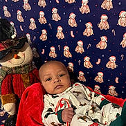 Amari is registered to the contest to win money with this photo: baby, candy_cane, holiday_pajamas, red_blanket, snowman_doll, top_hat, teddy_bear_pattern, blue_background, christmas_theme, festive, child, indoor, toy, infant, smiling, face, holiday, cute, seasonal, cozy
