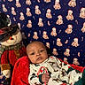 baby, candy_cane, holiday_pajamas, red_blanket, snowman_doll, top_hat, teddy_bear_pattern, blue_background, christmas_theme, festive, child, indoor, toy, infant, smiling, face, holiday, cute, seasonal, cozy