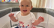 Riley joined the competition — help win amazing prizes! baby, bare_feet, child, curtains, family_photo, hands, happy, home, indoor, infant, kitchen, patriotic_clothing, playpen, portrait, sitting, smiling, star_pattern, striped_clothing, sunlight, white_shirt