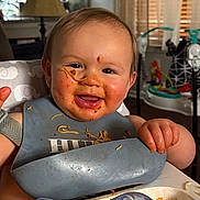 Riley joined the competition — help win amazing prizes! baby, child, toddler, high_chair, bib, food, noodles, pasta, sauce, messy_face, smiling, happy, sitting, indoors, kitchen, dining, bottle, toy, portrait, meal