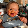baby, child, toddler, high_chair, bib, food, noodles, pasta, sauce, messy_face, smiling, happy, sitting, indoors, kitchen, dining, bottle, toy, portrait, meal