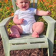 Riley joined the competition — help win amazing prizes! baby, child, outdoor, flower, lily, green_chair, smiling, sunlight, nature, plants, grass, summer, happy, person, one_piece_outfit, barefoot, sitting, garden, daylight, flora